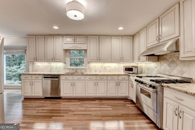 5507 Martina Way, Dunwoody, GA 30338 - kitchen with appliances with stainless steel finishes, under cabinet range hood, a sink, light wood finished floors, and healthy amount of natural light