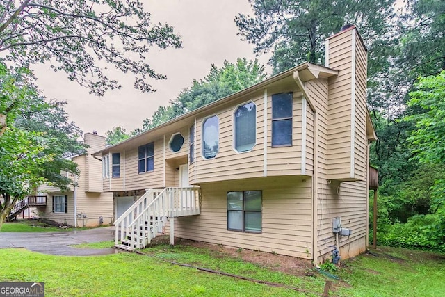 2218 Lowtrail Ct, Lithonia, GA 30058 - raised ranch featuring a chimney, an attached garage, a front yard, and driveway