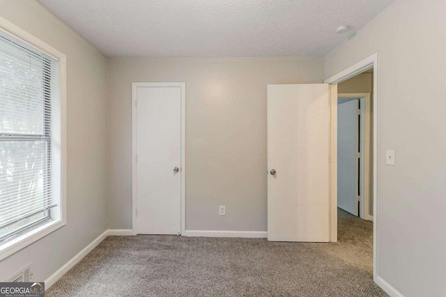 2218 Lowtrail Ct, Lithonia, GA 30058 - unfurnished bedroom with multiple windows, carpet floors, a textured ceiling, and baseboards