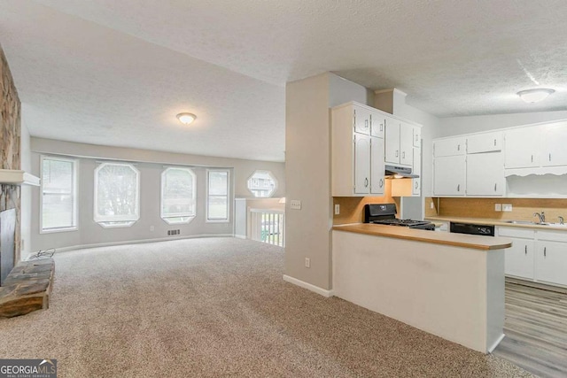 2218 Lowtrail Ct, Lithonia, GA 30058 - kitchen with gas stove, open floor plan, under cabinet range hood, a textured ceiling, and white cabinetry