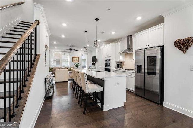 6635 Beacon Dr, Atlanta, GA 30328 - kitchen with stainless steel appliances, wall chimney exhaust hood, a ceiling fan, an island with sink, and recessed lighting