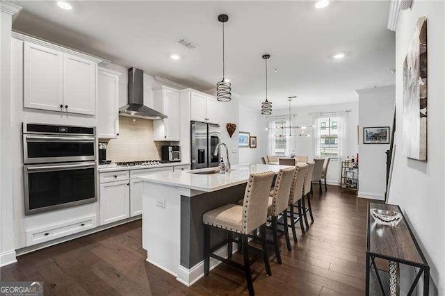 6635 Beacon Dr, Atlanta, GA 30328 - kitchen featuring wall chimney exhaust hood, stainless steel appliances, recessed lighting, a breakfast bar area, and white cabinets
