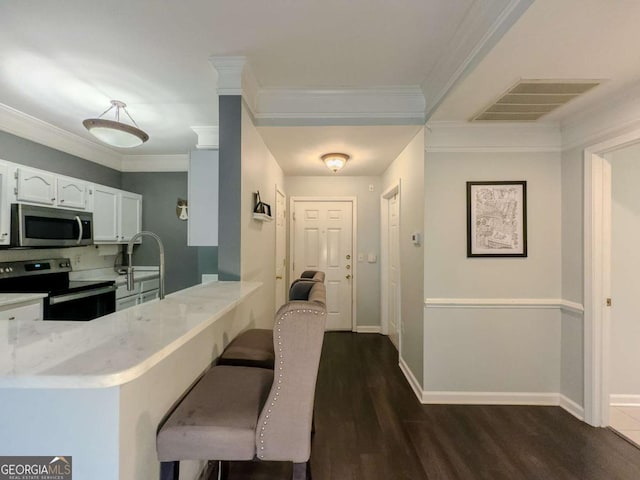 2700 Pine Tree Rd NE Unit 1013, Atlanta, GA 30324 - kitchen with stainless steel microwave, range with electric cooktop, white cabinetry, dark wood finished floors, and a peninsula