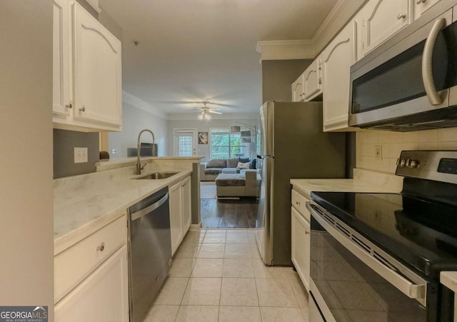 2700 Pine Tree Rd NE Unit 1013, Atlanta, GA 30324 - kitchen with stainless steel appliances, crown molding, ceiling fan, white cabinetry, and light tile patterned flooring