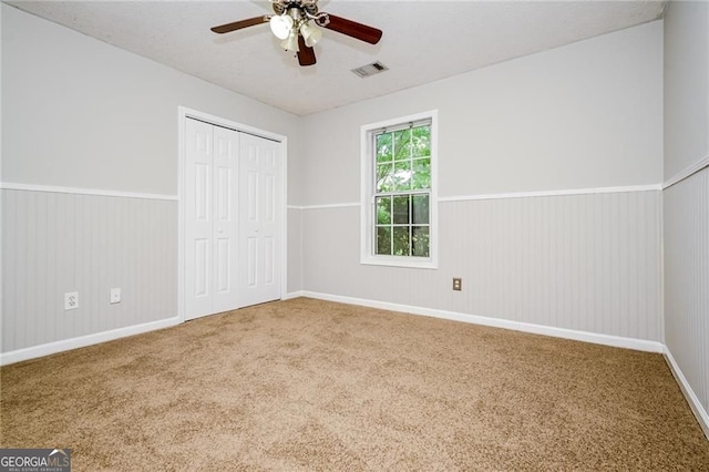 85 Chestnut Dr, Covington, GA 30016 - unfurnished bedroom featuring carpet floors, wainscoting, a closet, a ceiling fan, and baseboards