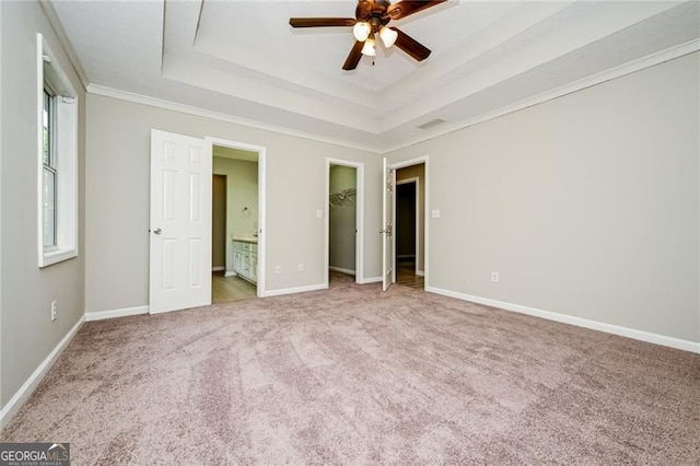 85 Chestnut Dr, Covington, GA 30016 - unfurnished bedroom with a tray ceiling, carpet, baseboards, a walk in closet, and crown molding