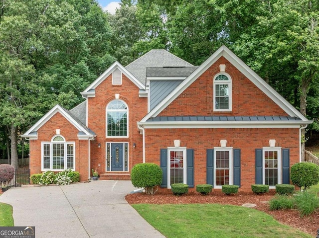 1440 Boundary Blvd, Suwanee, GA 30024 - traditional home featuring brick siding, a standing seam roof, a front yard, and roof with shingles