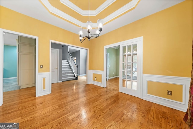 1440 Boundary Blvd, Suwanee, GA 30024 - unfurnished dining area with crown molding, stairway, a chandelier, wainscoting, and light wood-style floors