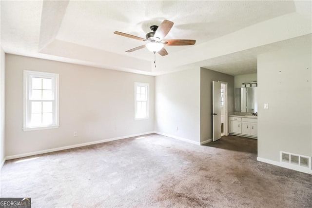 263 Austin Rd, Stockbridge, GA 30281 - unfurnished bedroom with a tray ceiling, dark colored carpet, a textured ceiling, and ensuite bath