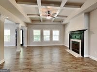 473 Cherry Creek Dr, Loganville, GA 30052 - unfurnished living room featuring a fireplace, baseboards, healthy amount of natural light, beam ceiling, and wood finished floors