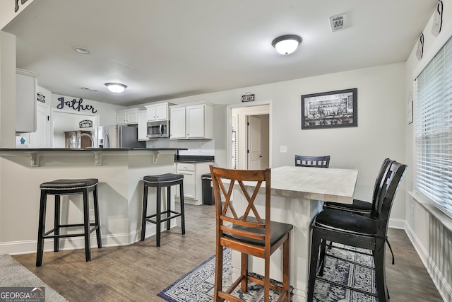 279 Brenna Ct, Luthersville, GA 30251 - kitchen with appliances with stainless steel finishes, a breakfast bar, dark countertops, and dark wood finished floors