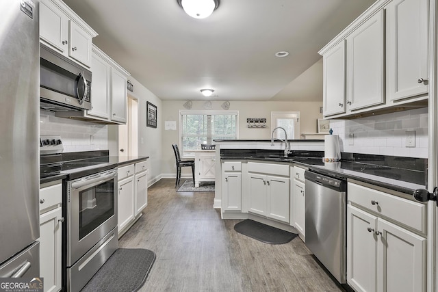 279 Brenna Ct, Luthersville, GA 30251 - kitchen featuring appliances with stainless steel finishes, a peninsula, a sink, tasteful backsplash, and white cabinets