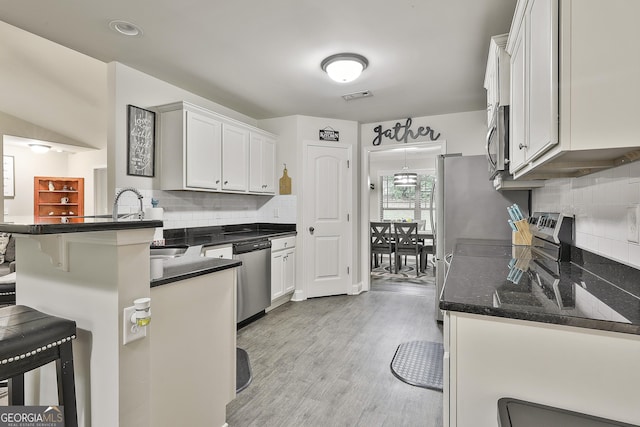 279 Brenna Ct, Luthersville, GA 30251 - kitchen featuring stainless steel appliances, a kitchen bar, a peninsula, tasteful backsplash, and light wood-type flooring