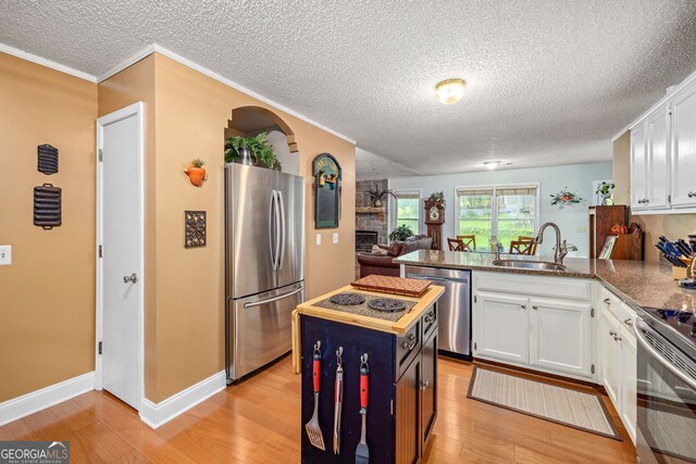 1526 Oakleaf Dr, Auburn, GA 30011 - kitchen featuring stainless steel appliances, a sink, a peninsula, white cabinetry, and a textured ceiling