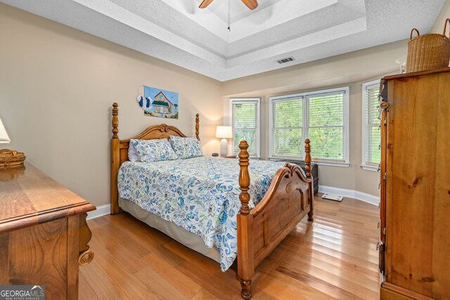 1526 Oakleaf Dr, Auburn, GA 30011 - bedroom with light wood finished floors, a tray ceiling, baseboards, and a ceiling fan