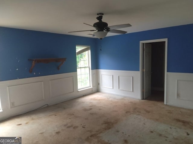 390 Burg Rd, Locust Grove, GA 30248 - unfurnished living room featuring wainscoting, carpet floors, a ceiling fan, and a decorative wall