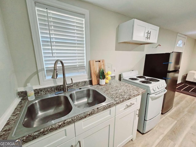 2977 5th St SW, Atlanta, GA 30315 - kitchen with white electric stove, light wood finished floors, white cabinetry, and freestanding refrigerator