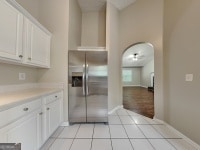 426 Summer Hill Cir, Stockbridge, GA 30281 - kitchen with stainless steel refrigerator with ice dispenser, light tile patterned flooring, white cabinets, light countertops, and arched walkways