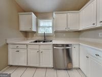 426 Summer Hill Cir, Stockbridge, GA 30281 - kitchen featuring stainless steel dishwasher, a sink, light countertops, and light tile patterned floors