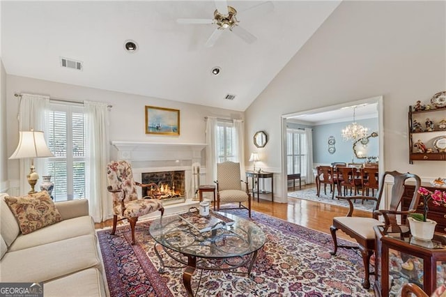 440 Carybell Ln, Alpharetta, GA 30004 - living room featuring ceiling fan, high vaulted ceiling, a lit fireplace, wood finished floors, and a chandelier