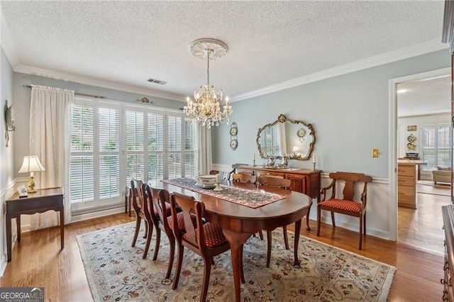 440 Carybell Ln, Alpharetta, GA 30004 - dining area featuring a chandelier, a textured ceiling, light wood-style flooring, crown molding, and a wainscoted wall