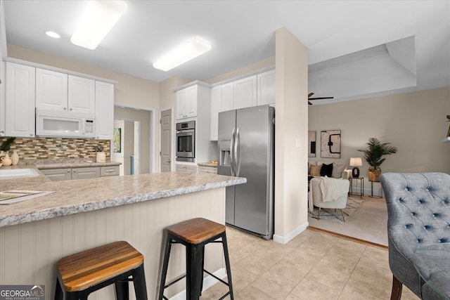 10 Wigwam Cir, Whitesburg, GA 30185 - kitchen with appliances with stainless steel finishes, light countertops, a peninsula, white cabinetry, and decorative backsplash