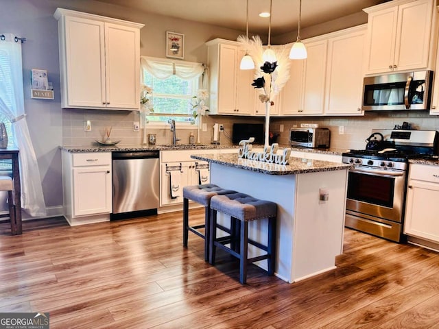 38 Lavender Ct, Dallas, GA 30132 - kitchen with stainless steel appliances, a sink, a kitchen island, white cabinetry, and light wood-style flooring