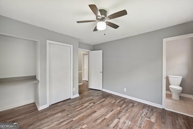 2676 Abington Dr, Snellville, GA 30078 - unfurnished bedroom featuring wood finished floors, baseboards, ensuite bathroom, and a ceiling fan