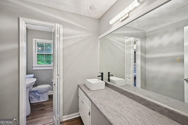 2676 Abington Dr, Snellville, GA 30078 - bathroom with wood finished floors, toilet, a textured ceiling, vanity, and baseboards