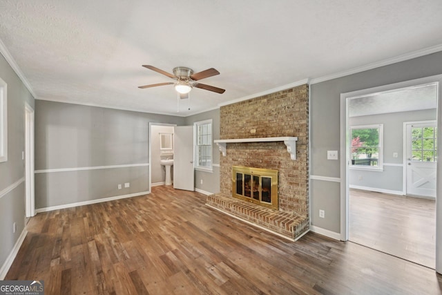2676 Abington Dr, Snellville, GA 30078 - unfurnished living room featuring a ceiling fan, wood finished floors, a brick fireplace, crown molding, and baseboards
