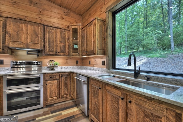 968 Hidden Valley Dr, Morganton, GA 30560 - kitchen featuring appliances with stainless steel finishes, a sink, wood walls, light stone counters, and glass insert cabinets