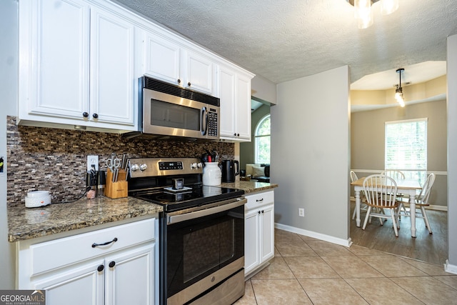 710 Newton Rd, Lagrange, GA 30240 - kitchen with stainless steel appliances, white cabinets, decorative backsplash, light tile patterned flooring, and light stone counters