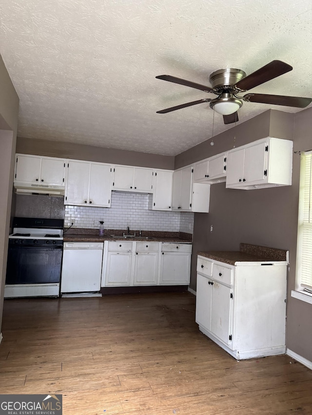 101 Sunset Ln, Newnan, GA 30263 - kitchen with white appliances, under cabinet range hood, ceiling fan, dark countertops, and white cabinetry