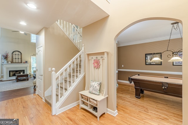 5767 Wembley Dr, Douglasville, GA 30135 - stairway featuring arched walkways, wood finished floors, crown molding, a ceiling fan, and a fireplace