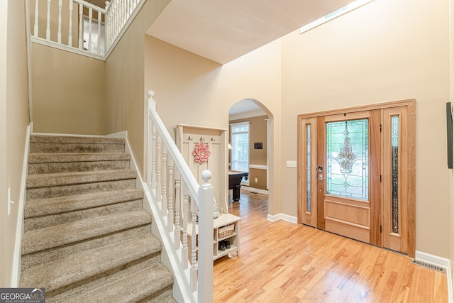 5767 Wembley Dr, Douglasville, GA 30135 - foyer entrance with arched walkways, a towering ceiling, stairway, and wood finished floors