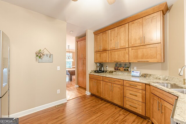 5767 Wembley Dr, Douglasville, GA 30135 - kitchen featuring light wood finished floors, light stone countertops, fridge with ice dispenser, and arched walkways