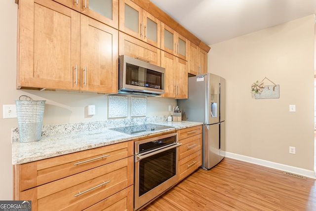 5767 Wembley Dr, Douglasville, GA 30135 - kitchen with stainless steel appliances, light wood-style floors, light stone countertops, and glass insert cabinets