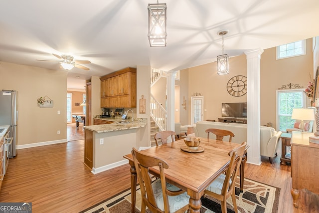 5767 Wembley Dr, Douglasville, GA 30135 - dining space with light wood finished floors, ornate columns, stairs, and a ceiling fan