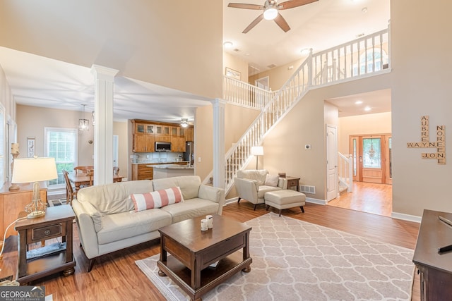 5767 Wembley Dr, Douglasville, GA 30135 - living area with a ceiling fan, ornate columns, light wood-style flooring, stairway, and a high ceiling