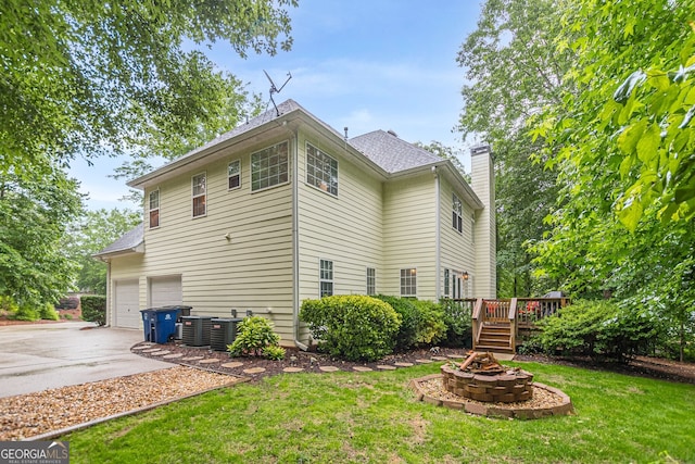 5767 Wembley Dr, Douglasville, GA 30135 - view of home's exterior with a fire pit, driveway, an attached garage, a chimney, and a wooden deck