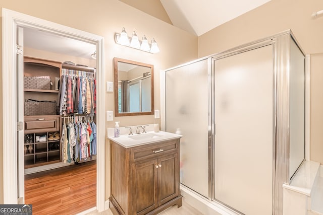 5767 Wembley Dr, Douglasville, GA 30135 - bathroom with lofted ceiling, vanity, a shower stall, a spacious closet, and wood finished floors
