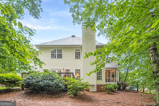 5767 Wembley Dr, Douglasville, GA 30135 - back of house featuring a sunroom, a deck, a chimney, and roof with shingles