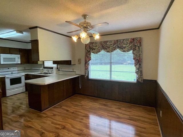 404 S Baker St, Glennville, GA 30427 - kitchen featuring white appliances, a peninsula, wainscoting, dark wood-type flooring, and crown molding