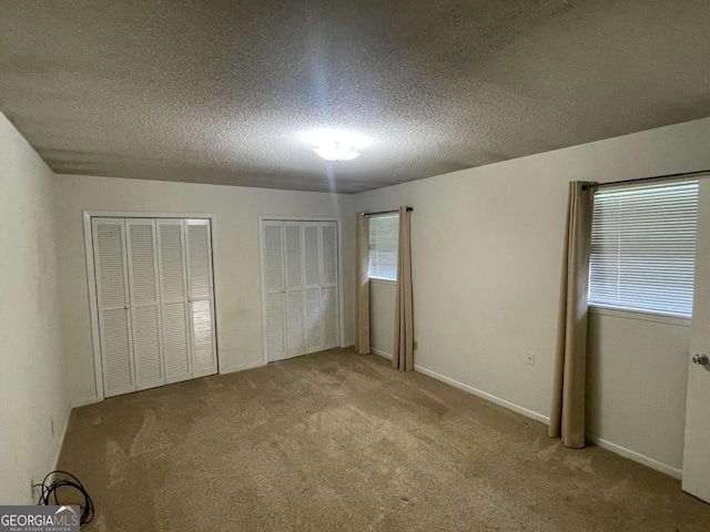 404 S Baker St, Glennville, GA 30427 - unfurnished bedroom featuring carpet floors, two closets, a textured ceiling, and multiple windows