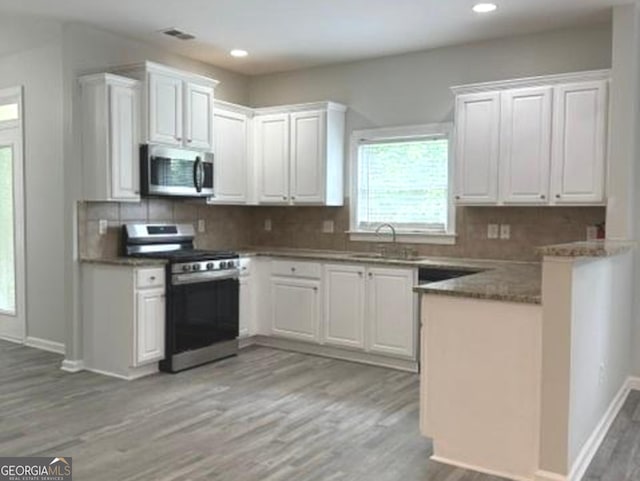 3700 Newhalem St SW, Atlanta, GA 30331 - kitchen with stainless steel appliances, light wood-style floors, white cabinets, backsplash, and recessed lighting