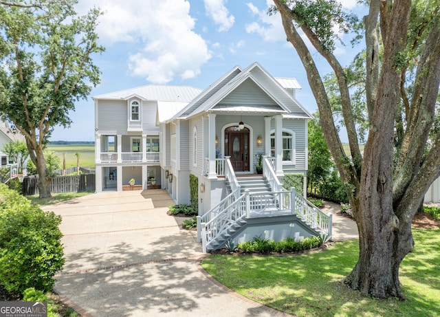 50 Frederica Oaks Ln, Saint Simons, GA 31522 - beach home featuring a porch, stairs, driveway, metal roof, and a front yard