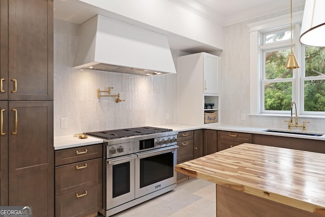 50 Frederica Oaks Ln, Saint Simons, GA 31522 - kitchen with range with two ovens, wood counters, wall chimney exhaust hood, a sink, and decorative backsplash