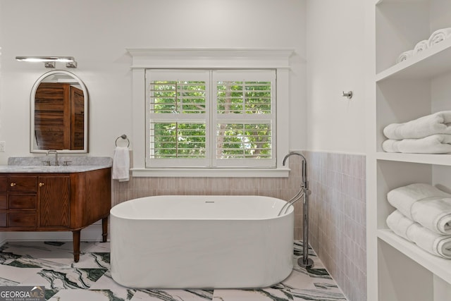 50 Frederica Oaks Ln, Saint Simons, GA 31522 - full bathroom with marble finish floors, vanity, a freestanding tub, tile walls, and wainscoting