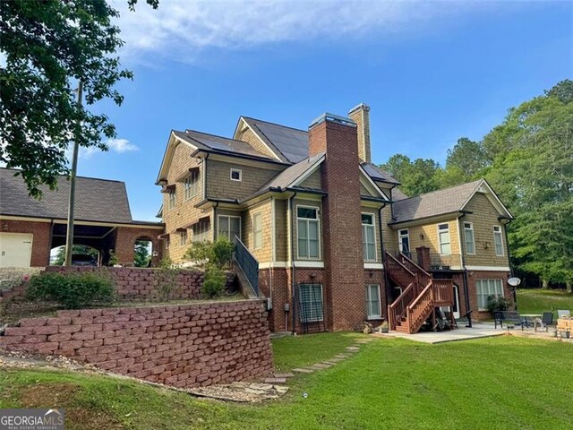 1695 Whitley Rd, Dacula, GA 30019 - back of house featuring a chimney, a patio area, a yard, and brick siding