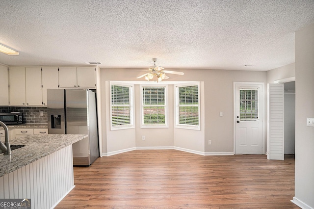 75 Plantation Ln, Locust Grove, GA 30248 - kitchen with stainless steel fridge with ice dispenser, black microwave, light wood-style floors, ceiling fan, and a textured ceiling